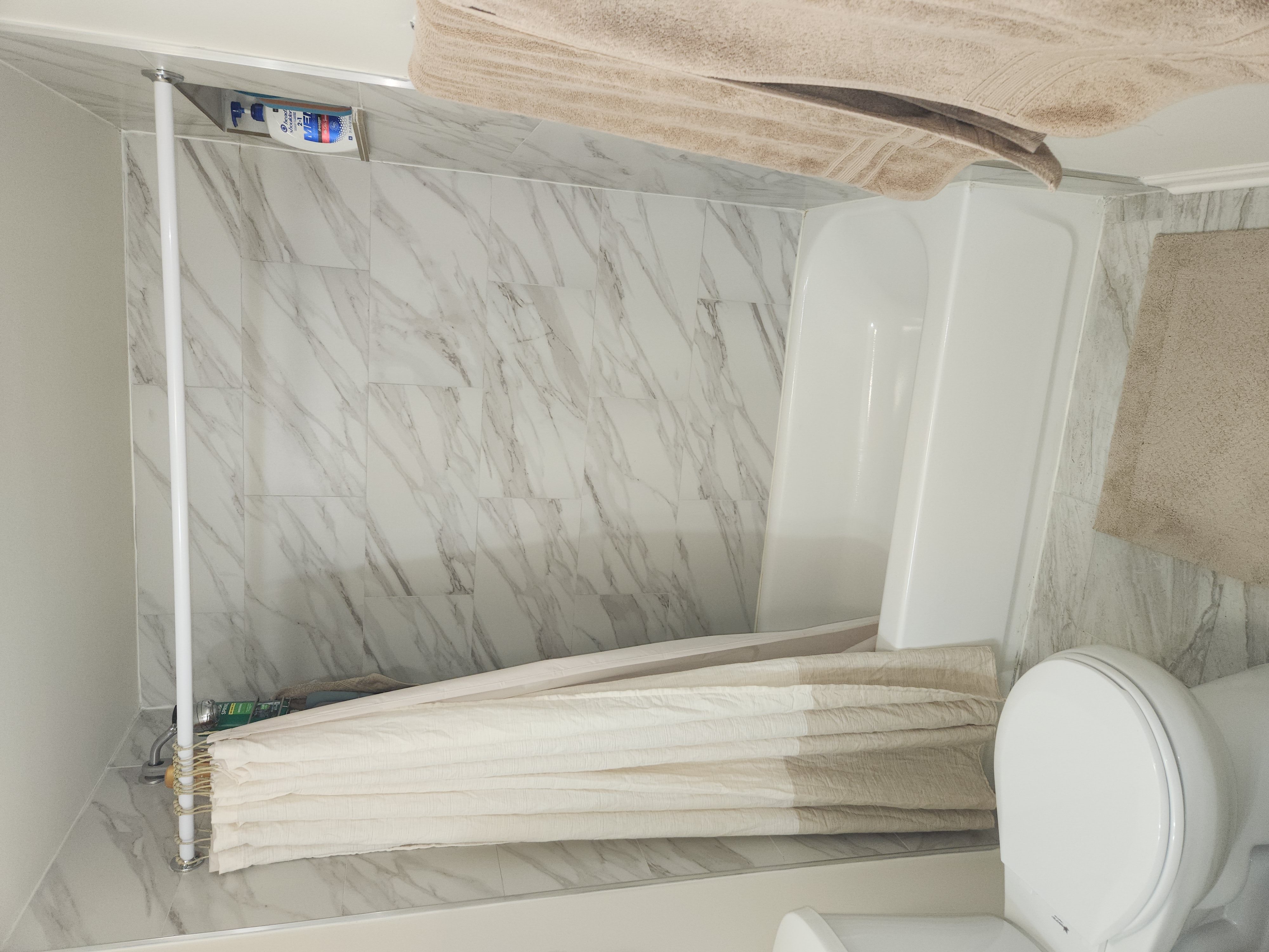 A white toilet with a towel hanging over the towel rack.